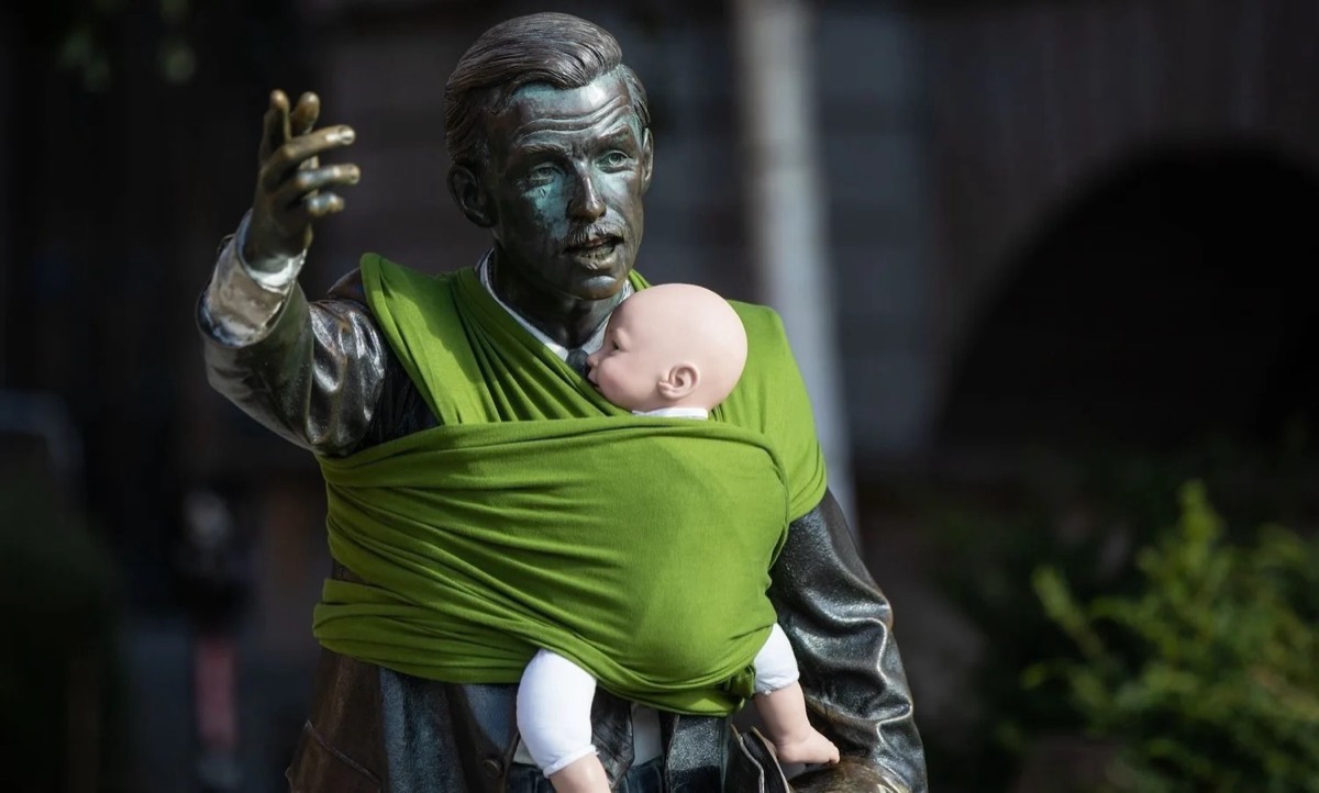 A city statue of a man wearing a baby in a sling, from a Dad Shift stunt